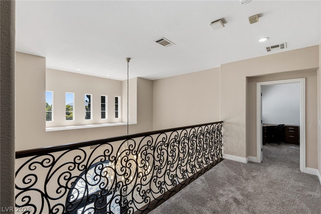 204 Satin Mist Court, Las Vegas, NV 89144 An upper-level hallway overlooks the lower floor through decorative wrought iron railings under high ceilings.