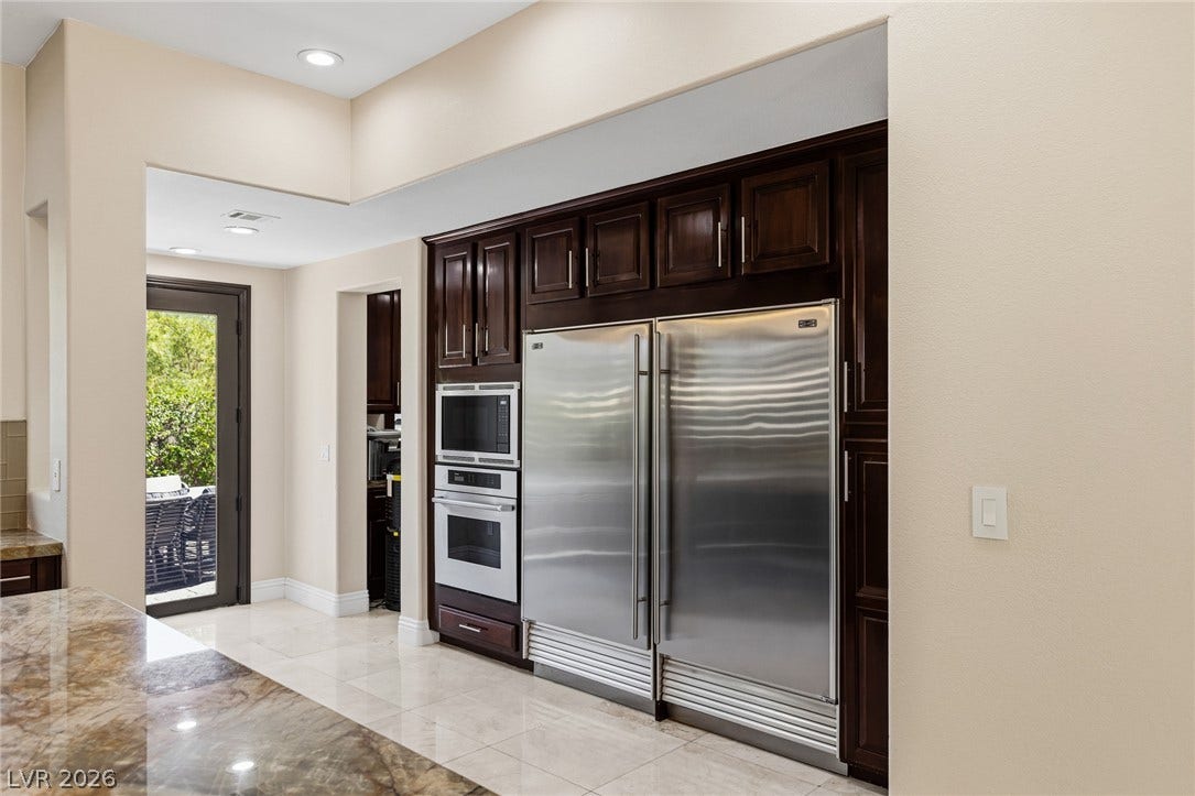 204 Satin Mist Court, Las Vegas, NV 89144 Rich dark wood cabinetry frames integrated stainless steel appliances above polished stone tile flooring.