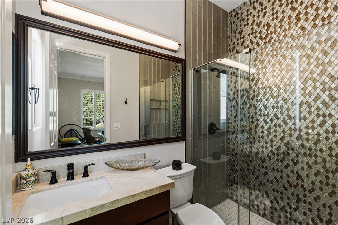204 Satin Mist Court, Las Vegas, NV 89144 Gleaming stone countertops and a modern glass shower elevate this refined bathroom space.