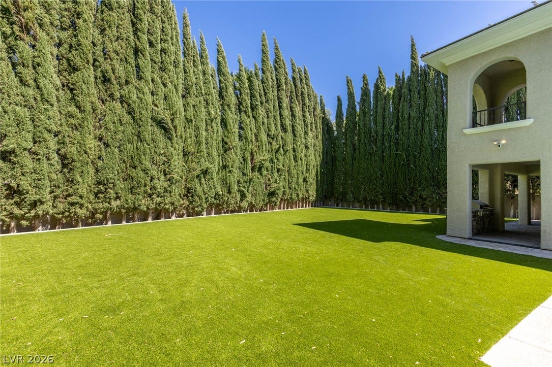 204 Satin Mist Court, Las Vegas, NV 89144 Towering privacy hedges border a manicured green lawn adjacent to the stucco exterior.
