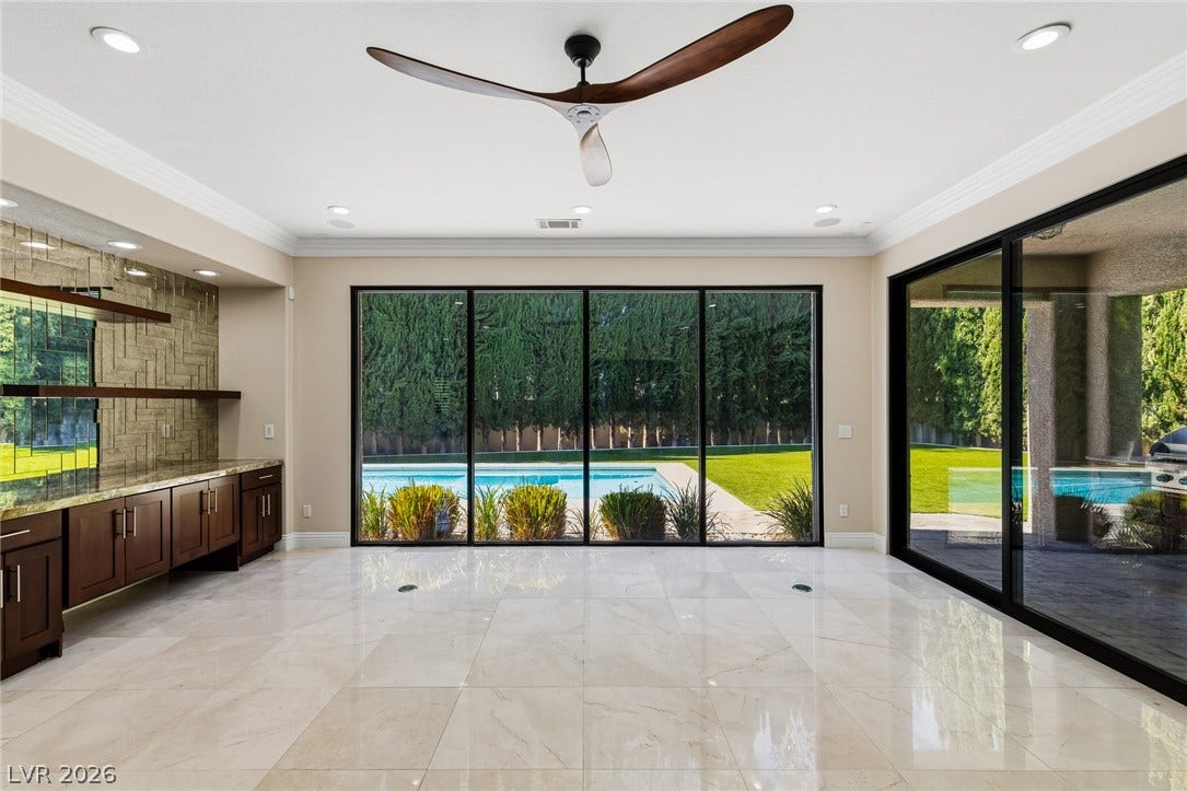 204 Satin Mist Court, Las Vegas, NV 89144 Gleaming tile floors and expansive glass doors overlook the backyard pool and lush lawn.
