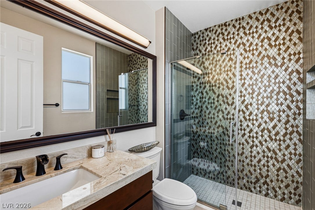 204 Satin Mist Court, Las Vegas, NV 89144 Ornate diamond patterned wall tiles and a stone counter elevate this modern bathroom.
