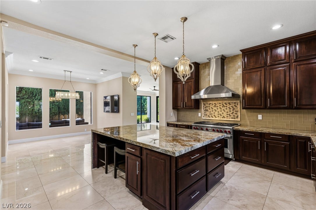 204 Satin Mist Court, Las Vegas, NV 89144 Rich dark wood cabinets and polished stone countertops elevate this expansive culinary space.