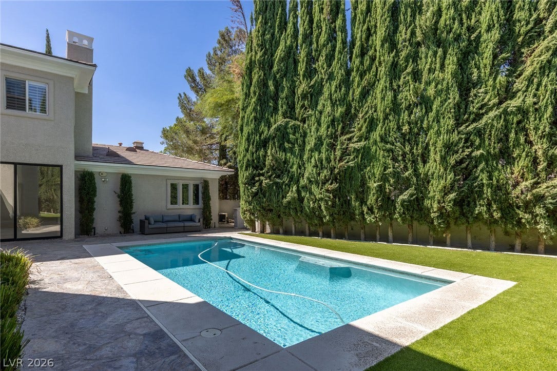 204 Satin Mist Court, Las Vegas, NV 89144 An inviting backyard oasis features a shimmering in-ground swimming pool framed by mature privacy trees.