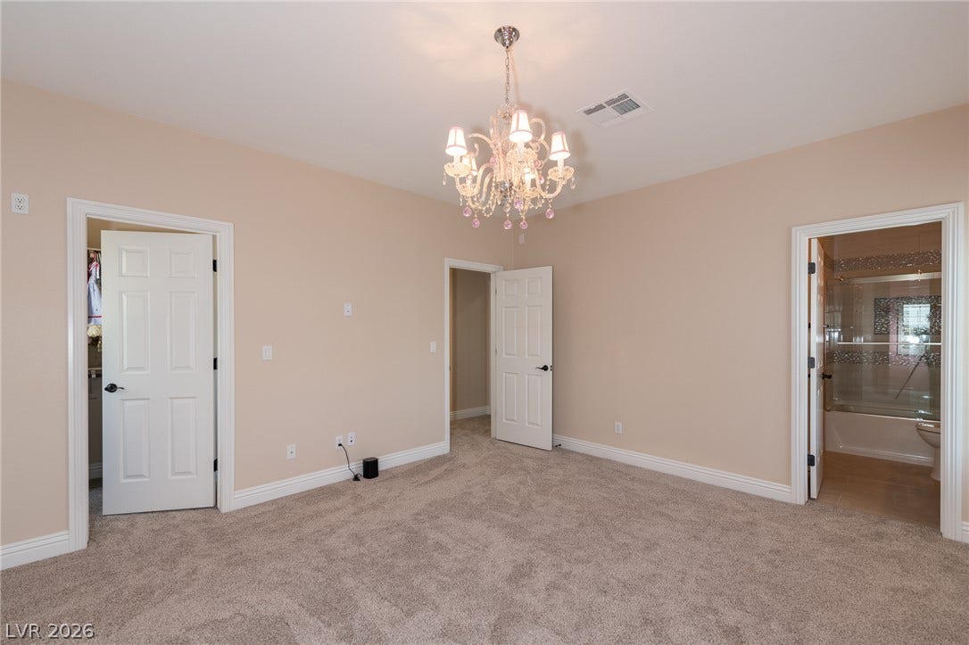 204 Satin Mist Court, Las Vegas, NV 89144 A spacious bedroom features plush carpeting, crown molding, and an elegant crystal chandelier.
