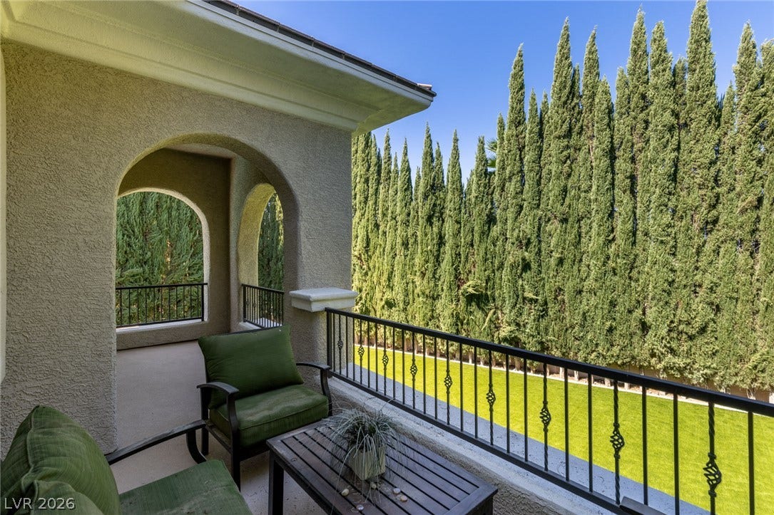 204 Satin Mist Court, Las Vegas, NV 89144 Stately stucco arches and classic metal railings frame views of towering cypress trees.