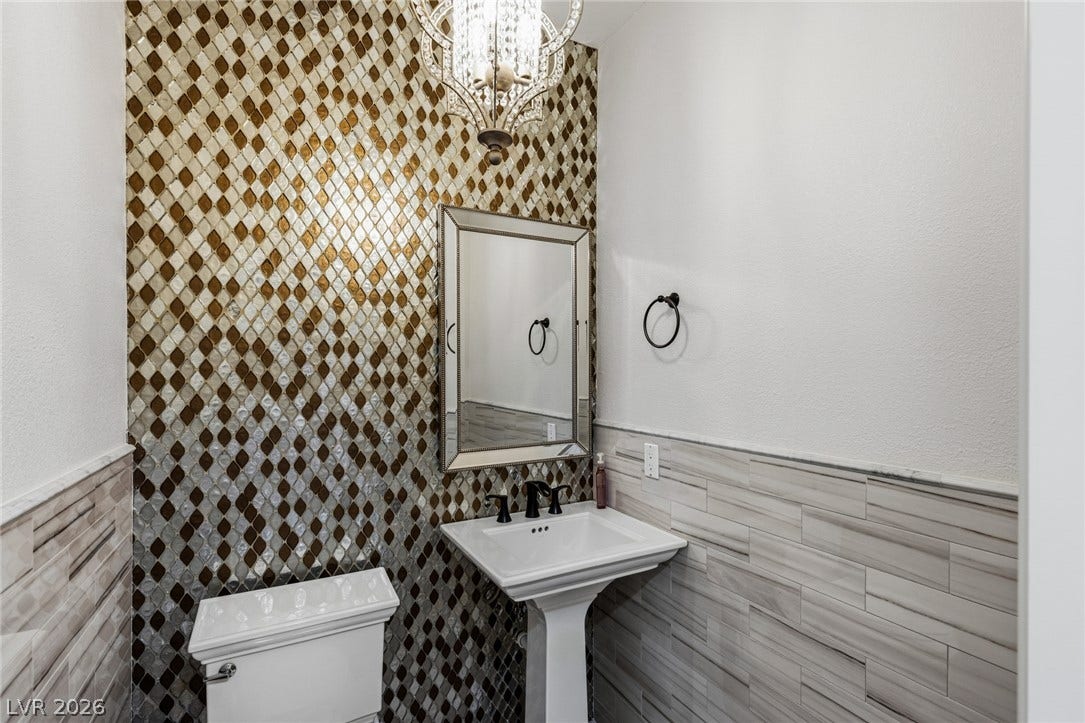 204 Satin Mist Court, Las Vegas, NV 89144 An elegant powder room features a custom mosaic accent wall and a classic pedestal sink.