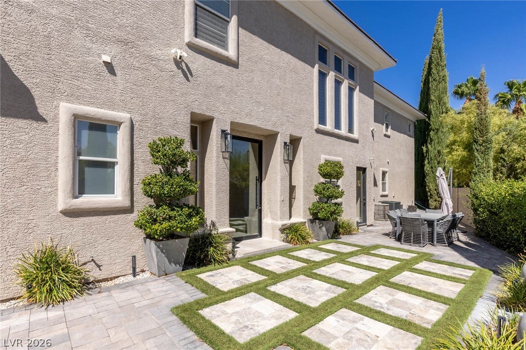204 Satin Mist Court, Las Vegas, NV 89144 Geometric stone pavers separated by grass accent the backyard patio of this modern stucco home.