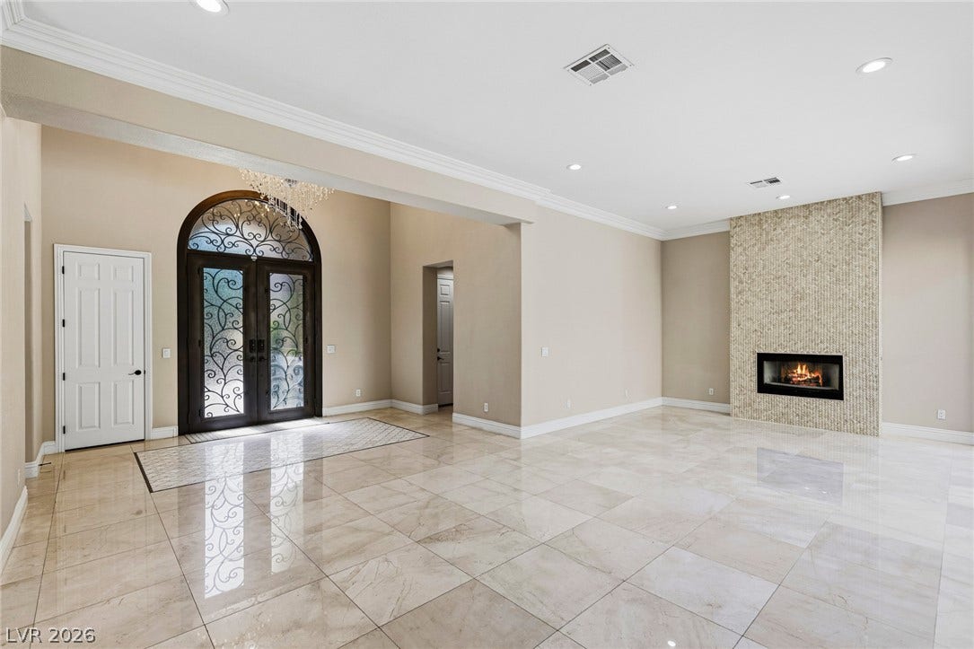204 Satin Mist Court, Las Vegas, NV 89144 Polished tile flooring, crown molding, and a sleek fireplace ground this light-filled entry and living space.