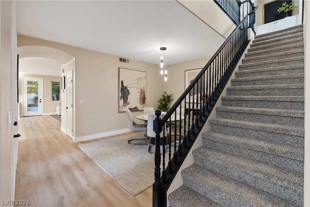 1662 Ravanusa Drive, Henderson, NV 89052 A carpeted staircase with a dark railing ascends from the wood-style flooring below.