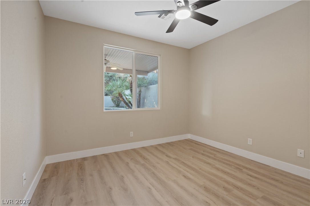 1662 Ravanusa Drive, Henderson, NV 89052 A window overlooks the backyard from this bedroom featuring wood-style flooring.