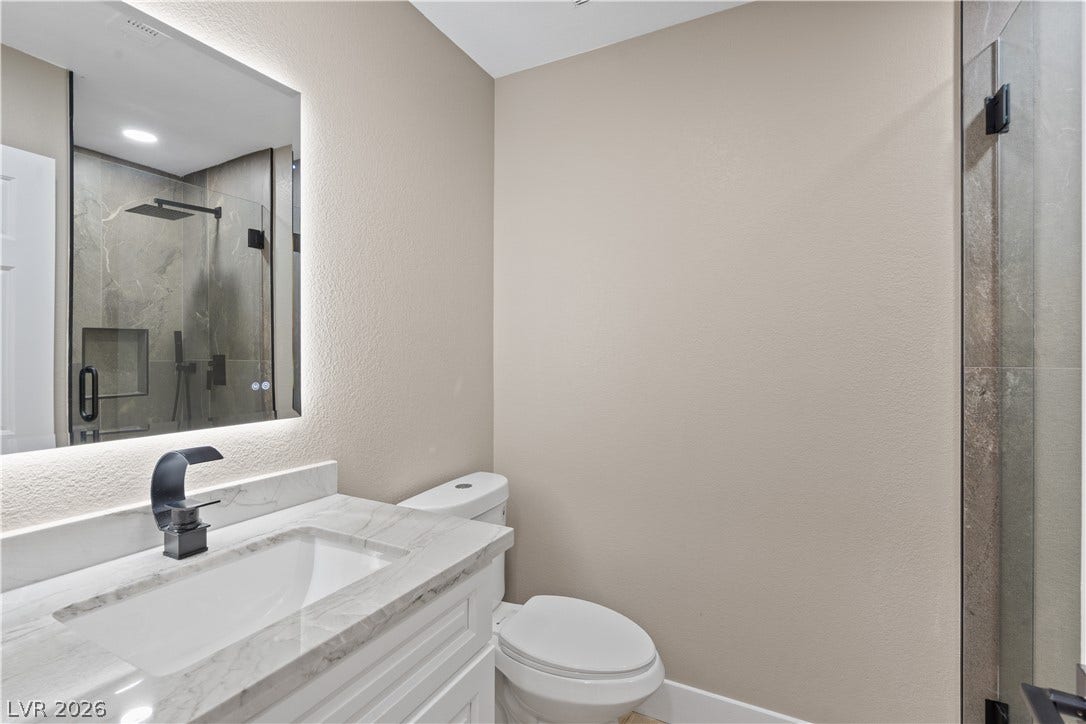 1662 Ravanusa Drive, Henderson, NV 89052 A marble vanity under a backlit mirror complements the contemporary walk-in shower finish.