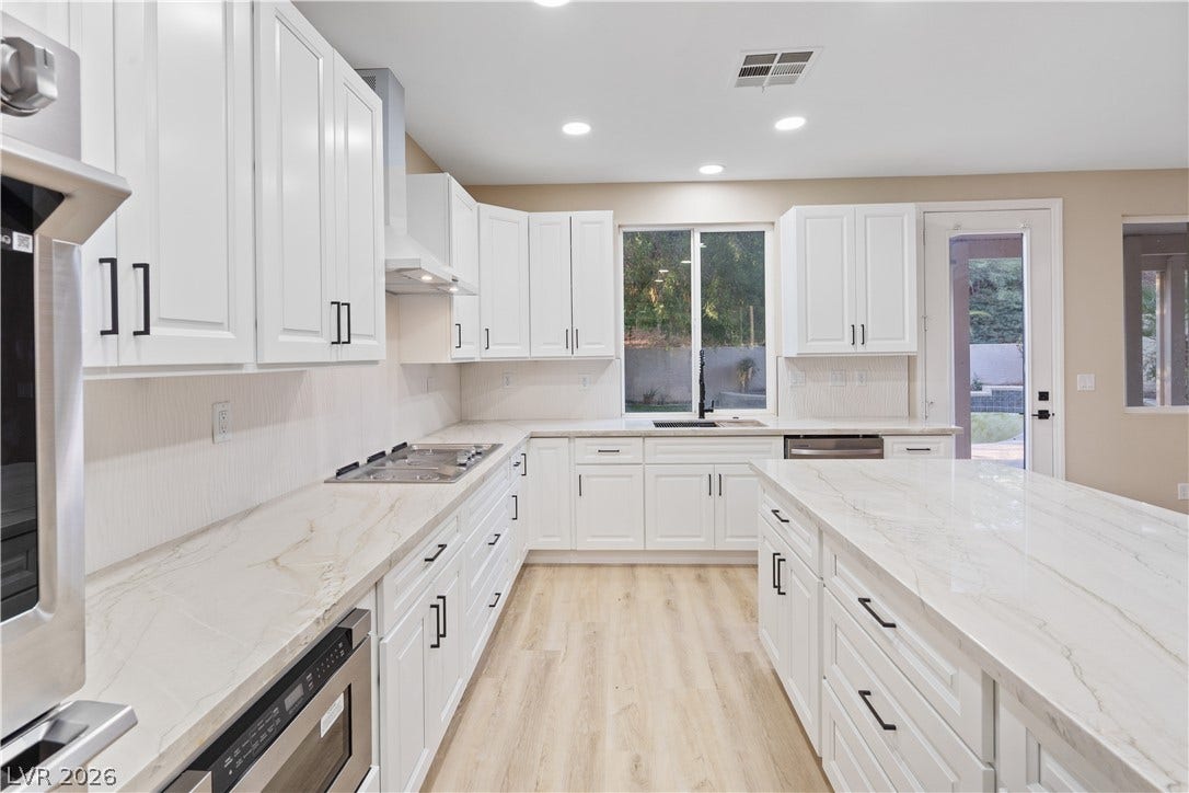 1662 Ravanusa Drive, Henderson, NV 89052 Elegant stone countertops and crisp white cabinetry define this bright, modern culinary space.