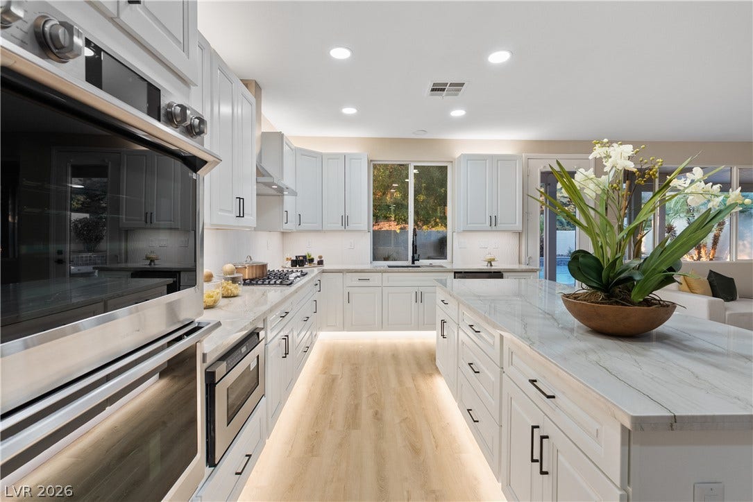 1662 Ravanusa Drive, Henderson, NV 89052 Crisp white cabinetry and expansive stone countertops define this modern, sunlit culinary space.