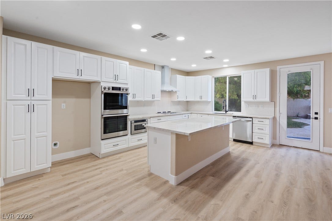 1662 Ravanusa Drive, Henderson, NV 89052 Recessed lighting illuminates a spacious culinary space featuring a large central island and hardwood flooring.