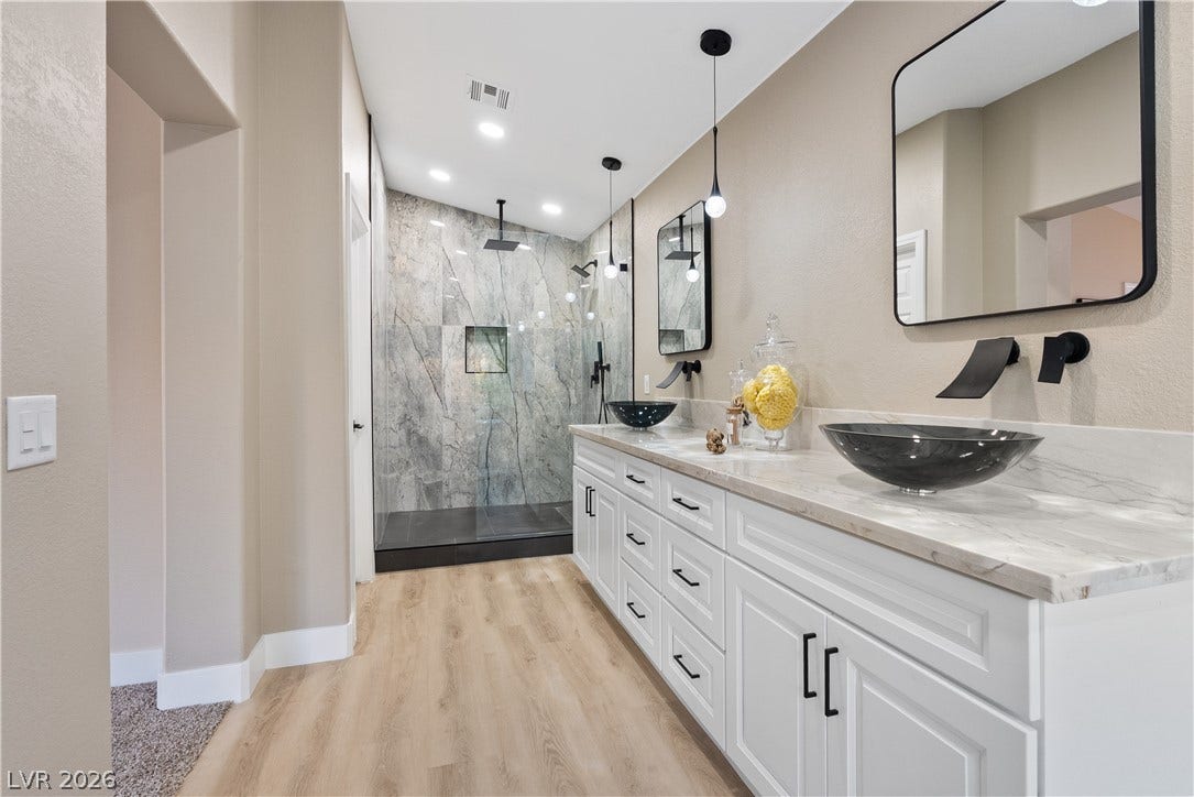 1662 Ravanusa Drive, Henderson, NV 89052 A long double vanity featuring stone counters and sleek vessel sinks updates this spacious bathroom.