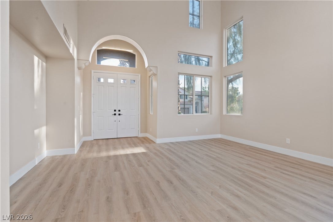 1662 Ravanusa Drive, Henderson, NV 89052 Double doors and towering windows define this light-filled entrance hall with warm wood flooring.