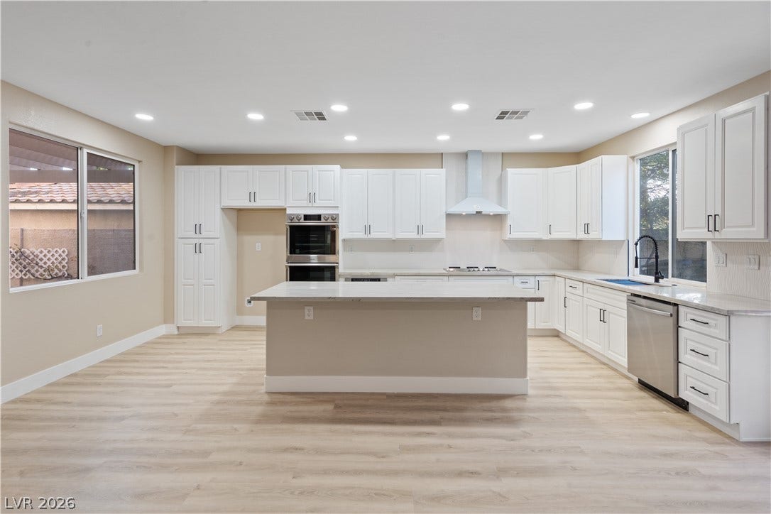 1662 Ravanusa Drive, Henderson, NV 89052 Recessed lighting illuminates this modern kitchen featuring a large central island and stone countertops.