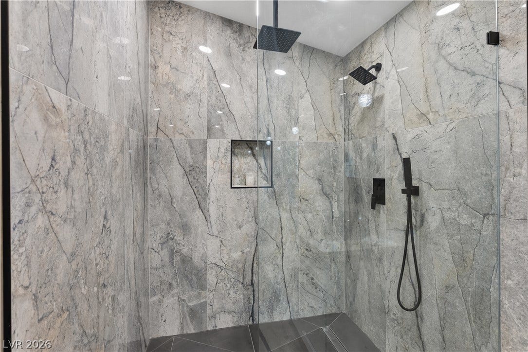 1662 Ravanusa Drive, Henderson, NV 89052 Dramatic floor-to-ceiling stone tiling and sleek modern fixtures elevate this walk-in shower.