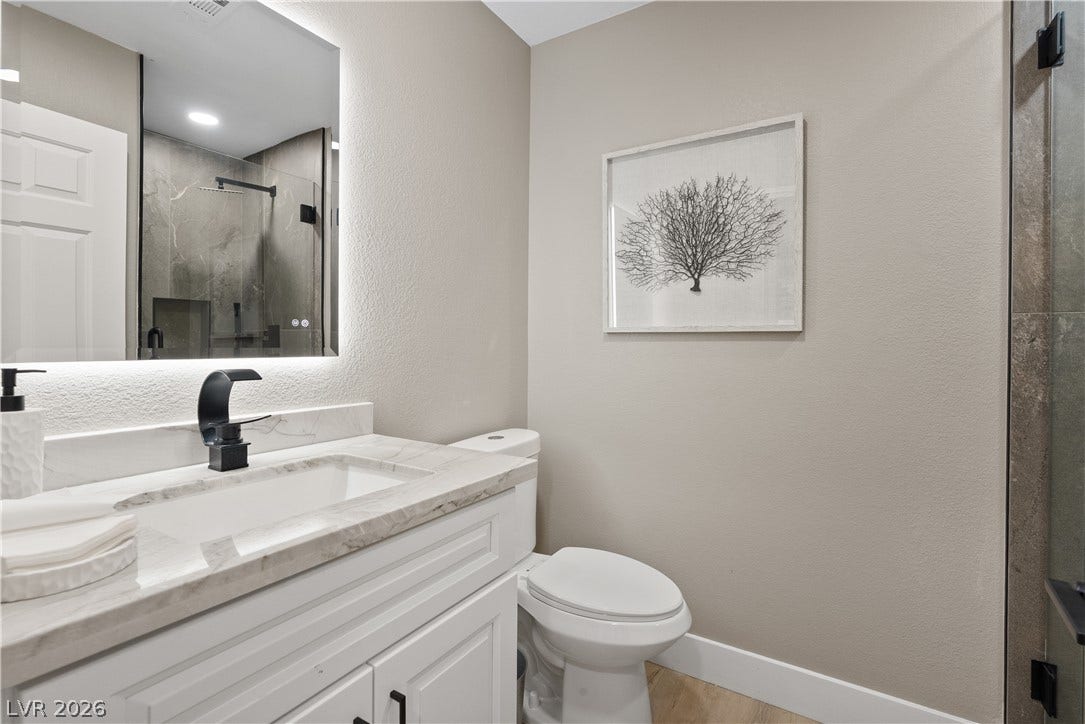 1662 Ravanusa Drive, Henderson, NV 89052 A modern vanity with stone counters pairs elegantly with a glass-enclosed walk-in shower.
