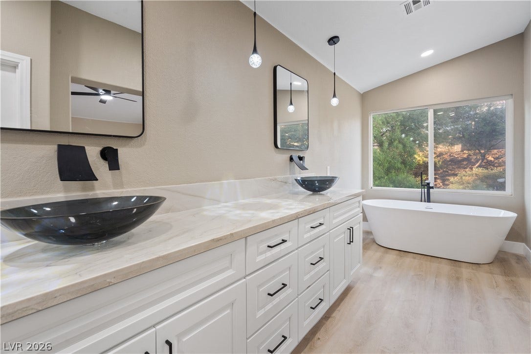 1662 Ravanusa Drive, Henderson, NV 89052 An elegant freestanding soaking tub rests beneath large windows framing peaceful wooded views.