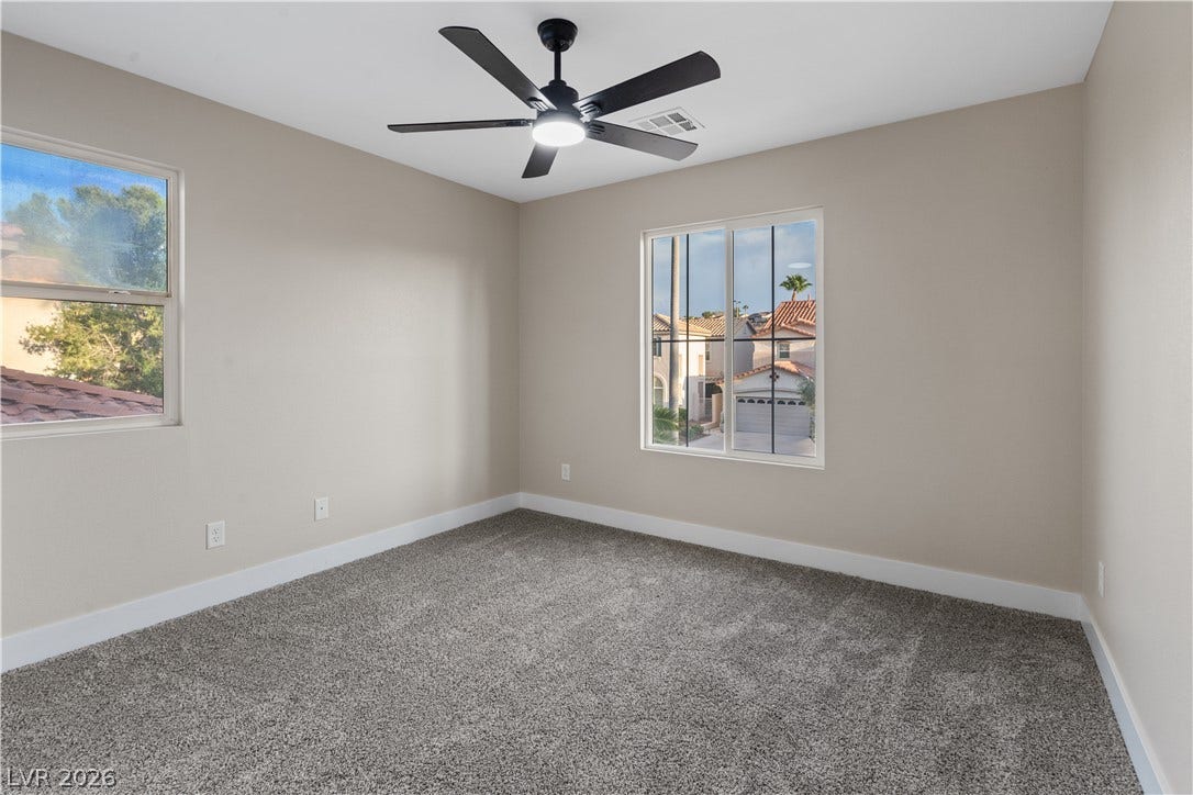 1662 Ravanusa Drive, Henderson, NV 89052 Plush carpeting and dual windows create a serene, neutral-toned secondary bedroom space.