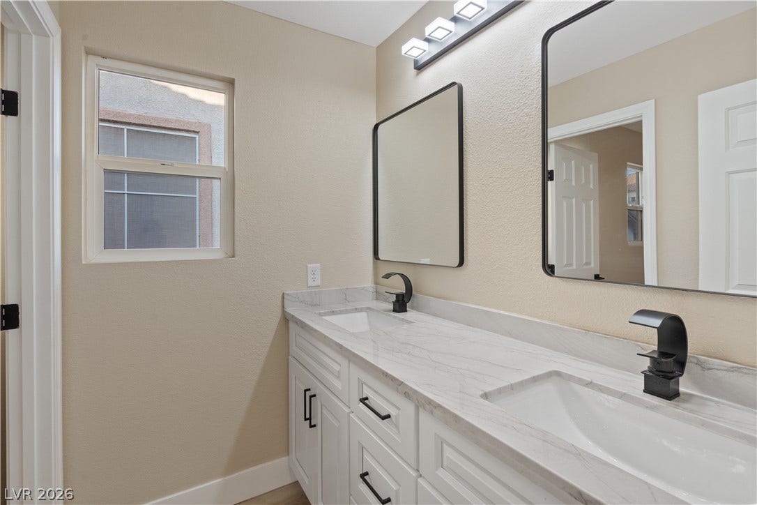 1662 Ravanusa Drive, Henderson, NV 89052 A spacious double vanity with marble countertops anchors this contemporary bathroom layout.