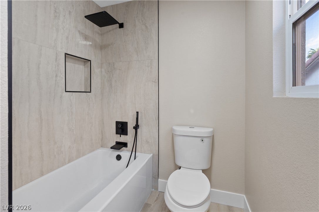 1662 Ravanusa Drive, Henderson, NV 89052 Modern tiled walls and a deep soaking tub create a refined guest bath experience.