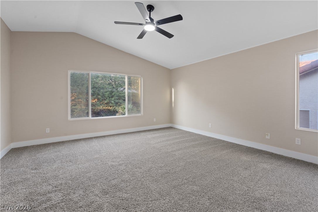 1662 Ravanusa Drive, Henderson, NV 89052 A spacious room features plush carpeting and a high vaulted ceiling with tall windows.