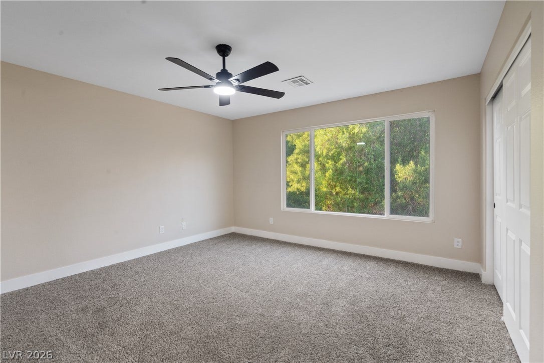 1662 Ravanusa Drive, Henderson, NV 89052 Plush carpeting and a large picture window frame serene tree-lined views in this restful bedroom.
