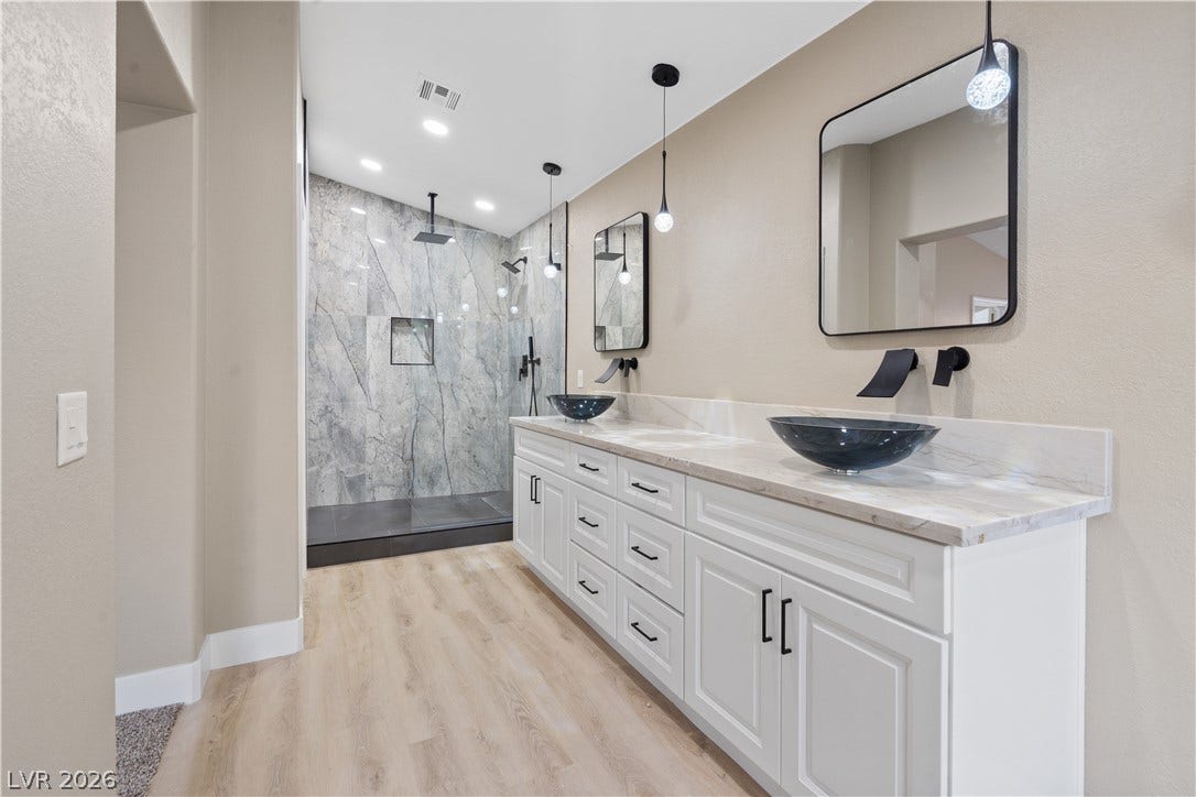 1662 Ravanusa Drive, Henderson, NV 89052 Double vanities with vessel sinks and a walk-in tile shower anchor this modern bathroom.