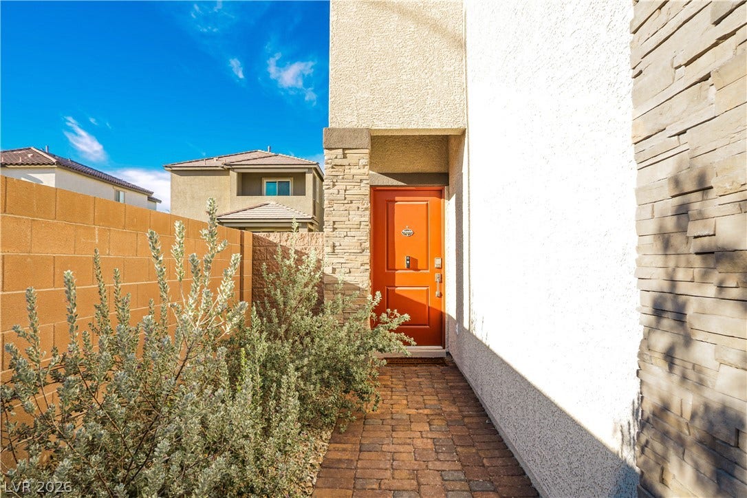 A stone-paved walkway leads directly to the covered private entrance of this modern home.