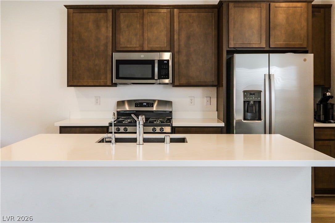 Rich wood cabinetry contrasts beautifully with clean white countertops in this contemporary kitchen.