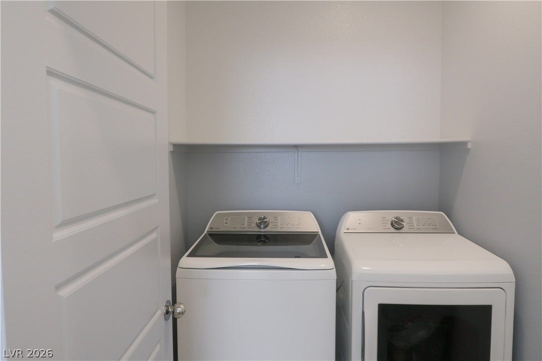 An organized laundry space comes complete with overhead shelving and contemporary panel doors.