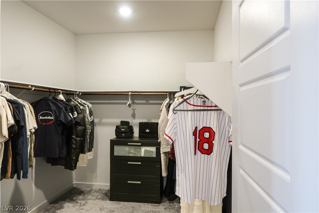 A spacious walk-in closet features plush carpeting and recessed lighting.