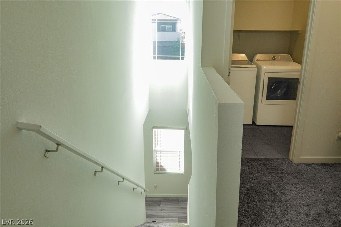 Natural light pours over the staircase landing leading directly toward the upper-level laundry area.