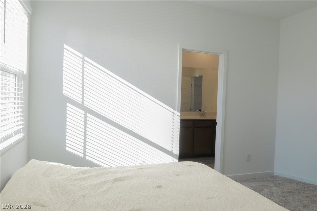 Sunlight filters through classic window treatments, illuminating the plush carpeting and clean plaster walls.