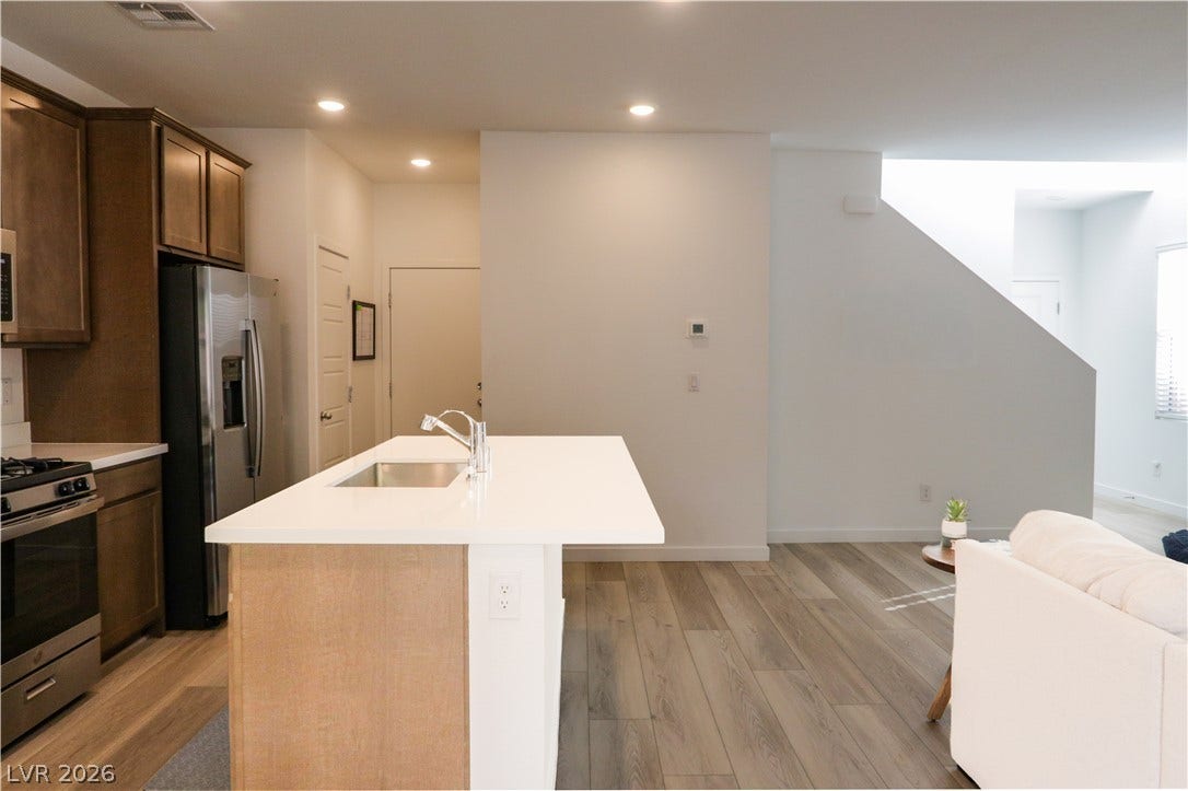 An open floorplan connects the modern kitchen island to the bright living areas.