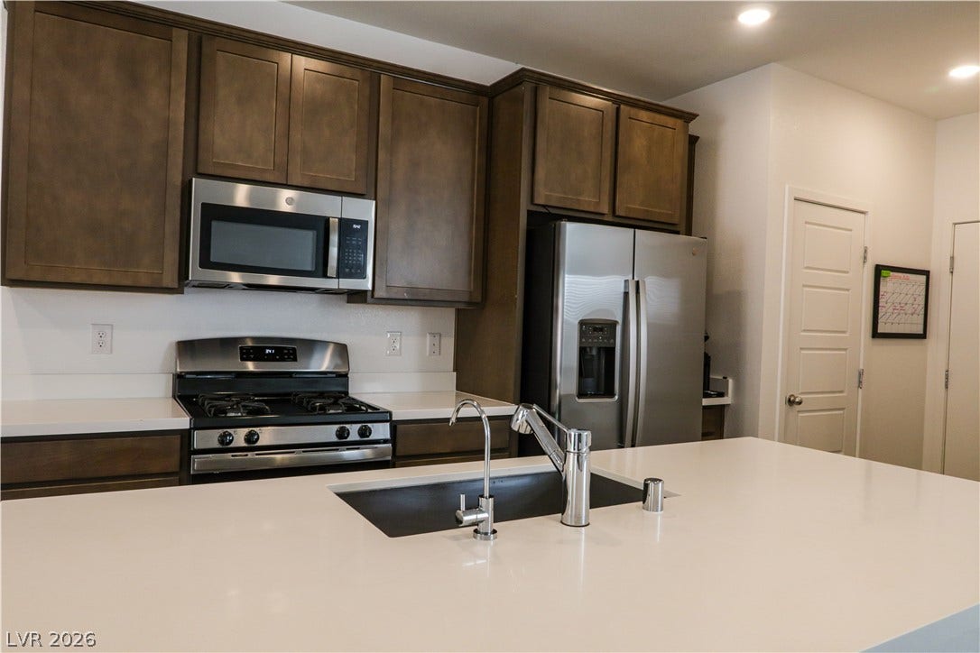 Rich wood cabinetry contrasts beautifully with clean white solid-surface countertops in this modern kitchen.