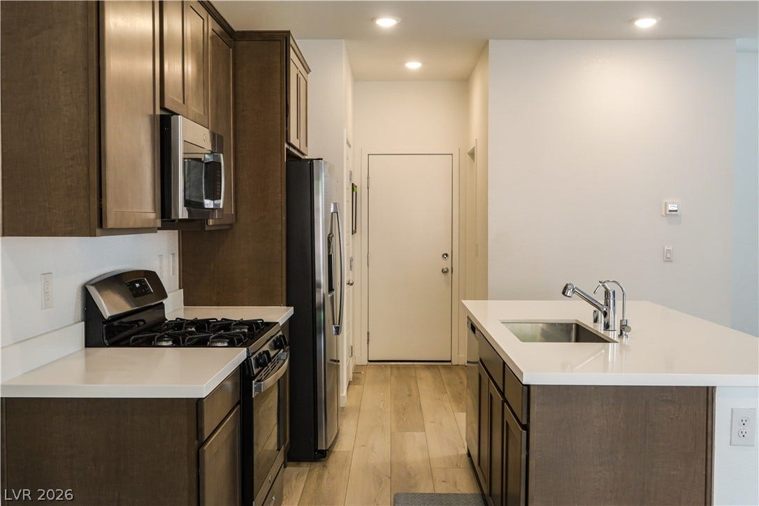 Rich wood cabinetry contrasts beautifully with clean white countertops in this contemporary kitchen.
