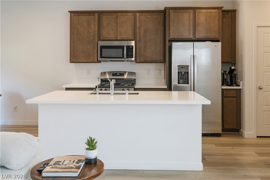 Rich wood cabinetry contrasts beautifully with clean white countertops and contemporary stainless appliances.