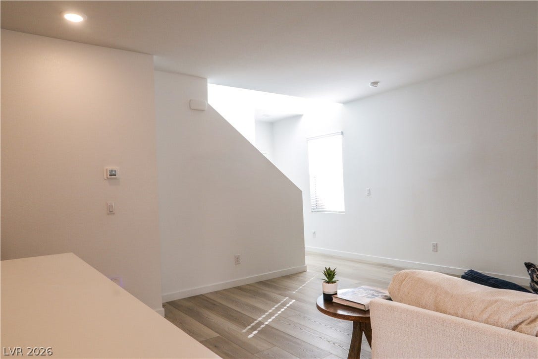 Gleaming wood-look floors complement clean white walls in this modern, sunlit living area.