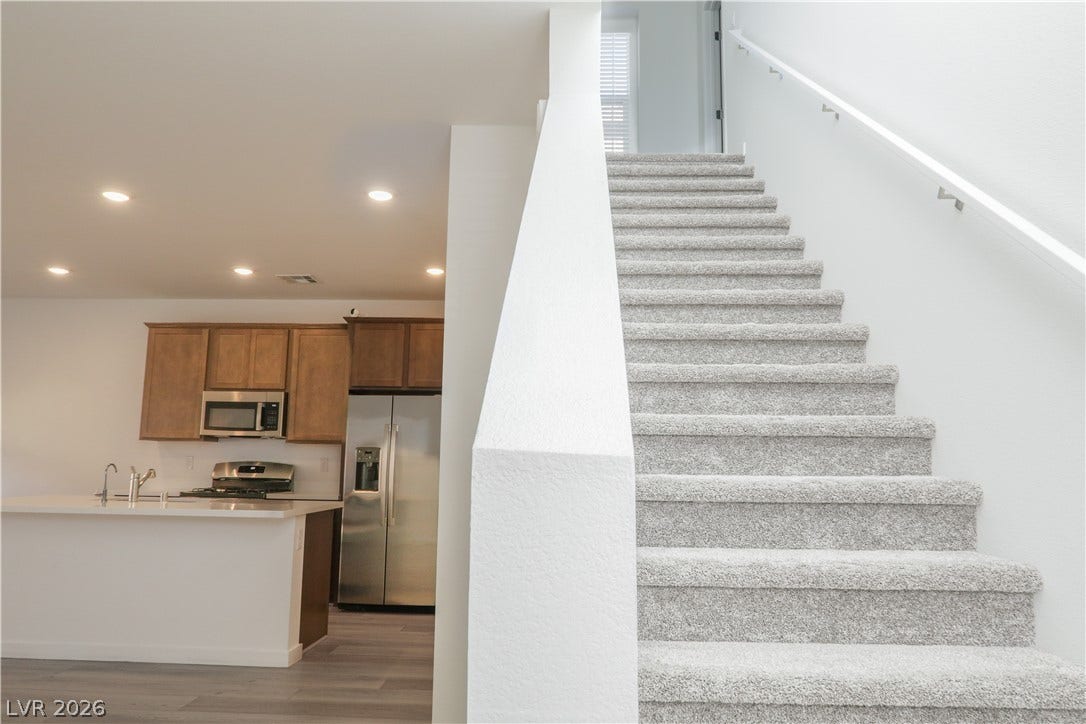 An open floorplan seamlessly connects the kitchen and dining area to the upper level stairs.