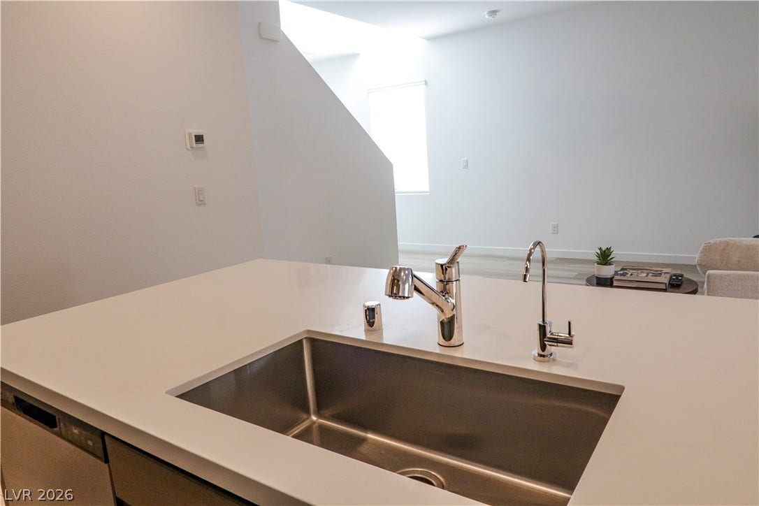 An undermount sink integrates seamlessly into the clean kitchen island overlooking the open living space.