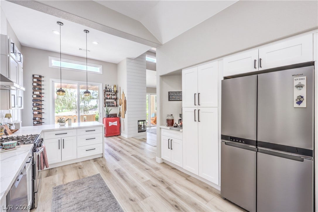 8211 Round Hills Circle, Las Vegas, NV 89113 This kitchen presents a harmonious blend of style and utility, featuring bright cabinetry, modern appliances, and a seamless transition to the outdoors.