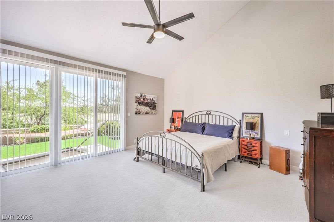8211 Round Hills Circle, Las Vegas, NV 89113 This primary bedroom provides comfortable carpeting and direct outdoor access through large sliding glass doors.