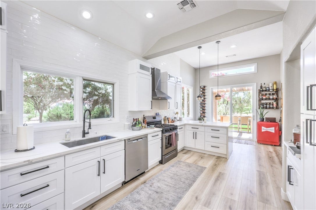 8211 Round Hills Circle, Las Vegas, NV 89113 A well-lit kitchen with sleek appliances and abundant natural light from multiple windows and sliding glass doors.