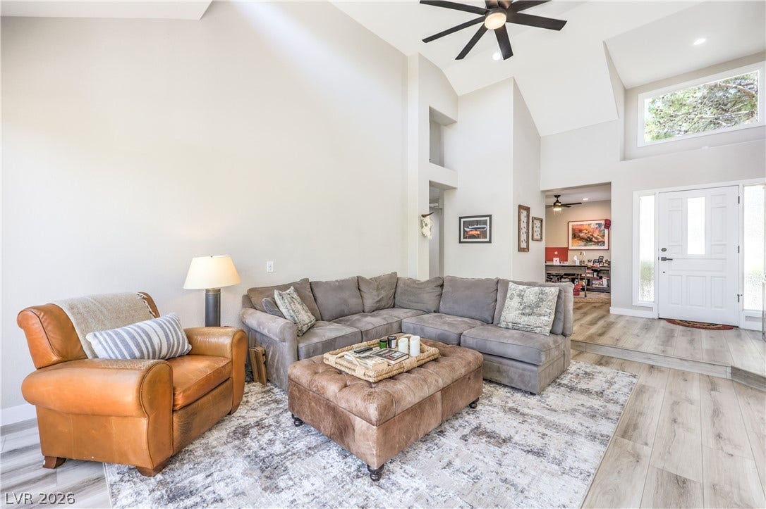 8211 Round Hills Circle, Las Vegas, NV 89113 A spacious living area features high vaulted ceilings and light wood flooring leading to a welcoming entryway.