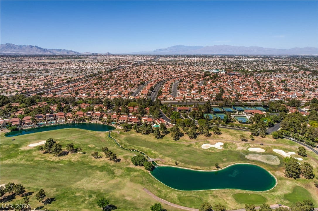 8211 Round Hills Circle, Las Vegas, NV 89113 An aerial panorama reveals a vast residential community intertwined with a verdant golf course and its tranquil water features.