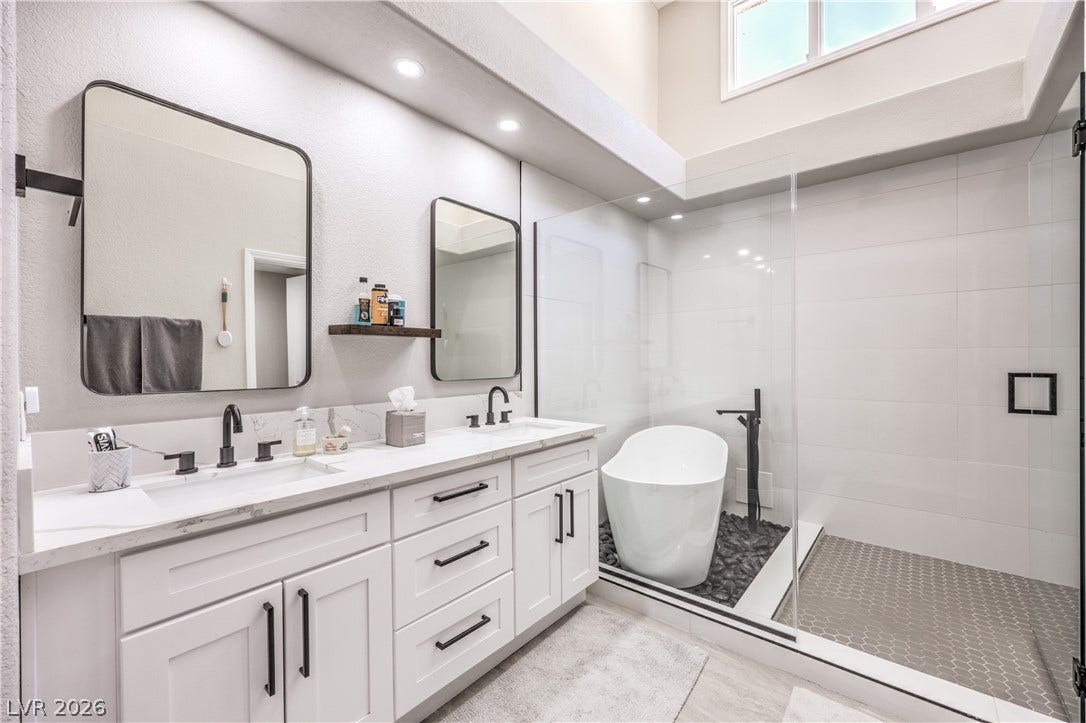 8211 Round Hills Circle, Las Vegas, NV 89113 Luxurious bathroom retreat features a dual vanity, an elegant freestanding soaking tub, and a spacious glass-enclosed shower.